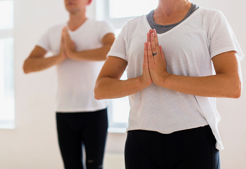 A group of people practicing Medical Qigong indoors, standing in a circle with focused expressions, performing gentle movements.